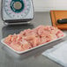 A white CKF foam meat tray holding raw chicken meat on a counter.