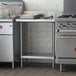 A Regency stainless steel work table with undershelf in a commercial kitchen.