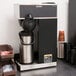 A Bunn commercial pourover coffee maker on a counter with a coffee pot.