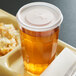 A clear plastic lid on a Dinex tumbler next to a plate of food.