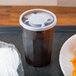 A tray with a plastic cup and lid on a table with a plate of food.