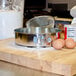 A Winco light tin springform cake pan on a wooden cutting board.