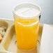 A translucent plastic lid on a white tray with a glass of orange juice and food.