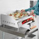 A woman using an Avantco electric countertop griddle to cook food.