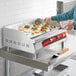 A woman using an Avantco electric countertop griddle to cook food.