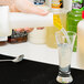 A person pouring liquid from a Carlisle white pourer into a glass.