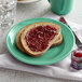 A Tuxton Concentrix cilantro plate with a piece of bread with jam on it.