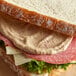 A sandwich with meat and cheese on a piece of bread with Admiration Dijon Mustard.