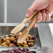 A person using Cambro beige plastic tongs to serve olives.