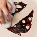 A hand using a cloth to clean up a stain on a counter.