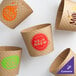 A group of 10-24 oz. natural Kraft customizable embossed coffee cup sleeves with brown designs.
