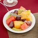 A Tuxton Colorado bright white narrow rim china plate with a fork in a bowl of fruit.