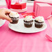 A person holding a cupcake on a Tuxton white oval china platter.