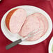 A Tuxton Colorado oval china platter with sliced meat and a fork.