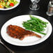 A Tuxton narrow rim oval china platter with food and a fork on a table.