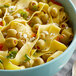 A blue bowl of pasta with olives and greens.