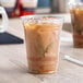 A clear 16 oz. plastic cold cup filled with iced coffee, featuring the Bare by Solo Eco-Forward logo.