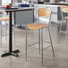 A Lancaster Table & Seating natural finish cafe bar stool at a table in a kitchen.