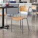 A Lancaster Table & Seating natural finish cafe chair next to a table.