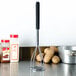 A Thunder Group potato masher with a soft grip handle mashing potatoes in a pot.