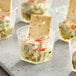 A group of Fineline clear plastic cups with food in them.
