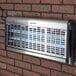 A Lavex Zap N Trap UV insect zapper bulb in a metal vent on a brick wall.