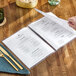 A person holding a clear menu on a table.