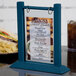 A Menu Solutions denim wood table tent on a table with a sandwich and chips.