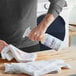 A person using Noble Chemical Vanish Laundry Pre-Spotter to spray a white towel.