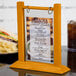 A Menu Solutions oak wood flip top table tent on a table with a menu.