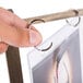 A hand using a metal ring to display a menu in a wood table tent.