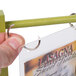 A hand holding a Menu Solutions lime wood flip top table tent with a metal clip.