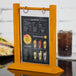 A Menu Solutions oak wood table tent on a table with a drink.