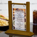 A walnut wood flip top table tent with a menu on a table.