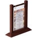 A Menu Solutions mahogany wood flip top table tent holding a menu on a table.