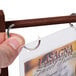 A hand holding a mahogany wood table tent with plastic sheet and rings.