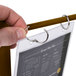 A hand holding a walnut wood flip top table tent with a menu card inside.