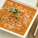 A bowl of lentil soup with parsley and a fork.