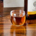 A GET stemless wine glass filled with brown liquid on a table in a cocktail bar.