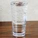 A GET stackable plastic mixing glass filled with ice water on a table.