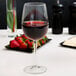 A Libbey wine glass filled with red wine on a table.