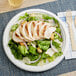 A plate of salad with chicken and vegetables on a EcoChoice Compostable Bagasse plate.