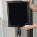 A person holding a black rectangular Aarco sign frame.