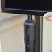 A person using a black Aarco stanchion sign frame to display a black sign.