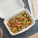 An EcoChoice compostable bagasse take-out container with food inside on a place mat.