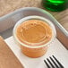 A Solo clear plastic souffle lid on a plastic container of food.