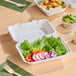 A white compostable plant fiber take-out container with a single compartment, shown holding a fresh salad.