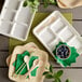 A white EcoChoice compostable tray with 6 compartments holding blueberries with a spoon.