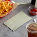 A basket of french fries on a table with a Sage 2-ply paper dinner napkin and a drink.