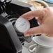 A hand using a Caffe De Aroma Green Tea single serve cup in a black coffee machine.